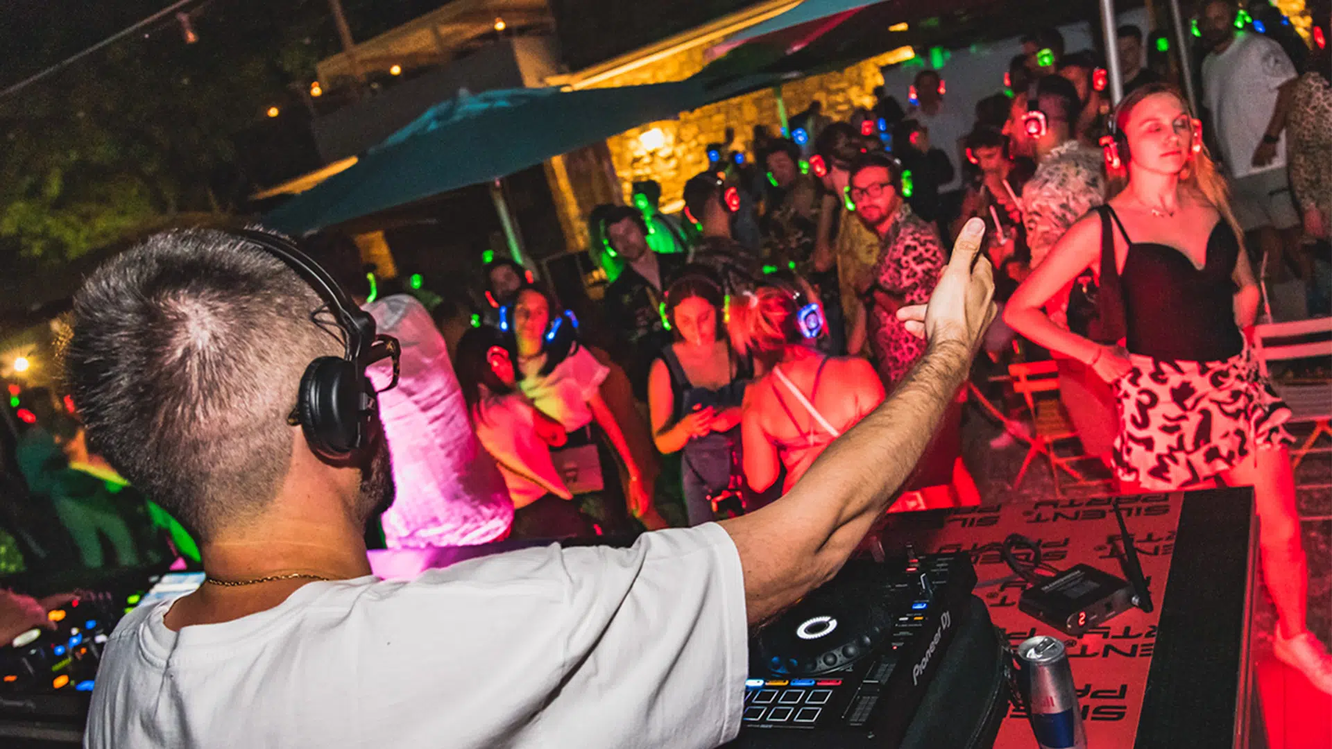 Silent party vs discoteca tradizionale — DJ e pubblico con cuffie wireless